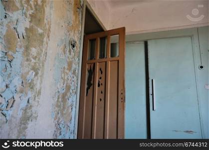 Broken door peeling wall and closet in empty abandoned house interior.