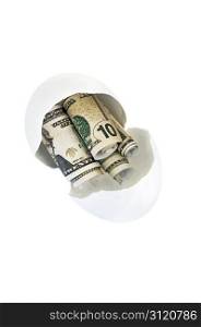 Broken egg shell with rolled up fake money to represent getting into a persons nest-egg. Isolated with a clipping path.