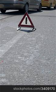 Broken glass from car on a road. Road sign attention