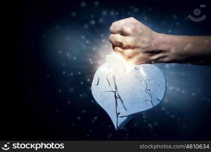 Broken heart. Close up of human hand breaking stone heart