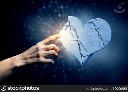 Broken heart. Close up of human hand breaking stone heart