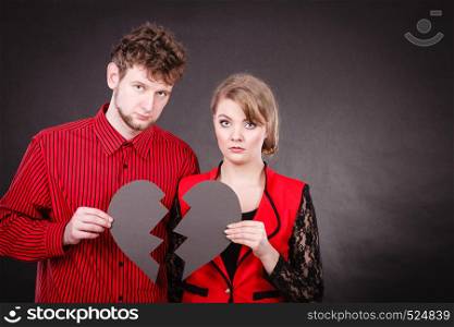 Broken heart difficult love concept. Sad unhappy couple woman and man holding paper red heart fixed with plaster bandage. Rift in relations.. Sad couple holds broken heart.