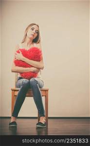 Broken heart love concept. Sad unhappy woman hugging red heart pillow