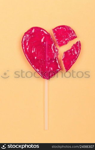 Broken lollipop candy heart love shape on yellow background