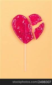 Broken lollipop candy heart love shape on yellow background