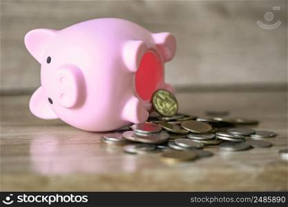Broken piggy bank with and coins on wooden background, saving money for education study or investment concept