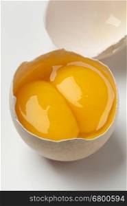 Broken raw fresh double yolk egg close up on white background