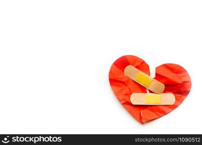 Broken red heart symbol with medical patch on white background, love concept. healing. Copyspace. Broken red heart symbol with medical patch on white background, love concept. healing