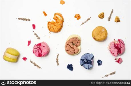 broken round macarons with crumbs on a white background, delicious dessert, top view