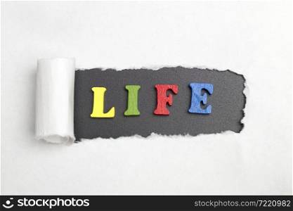 Broken sheet of paper behind the word life.. The word life.