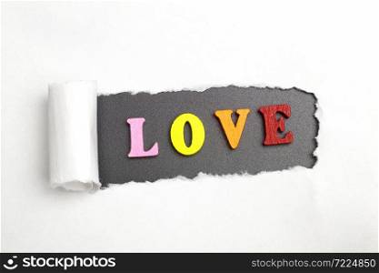 Broken sheet of paper behind the word love.. The word love.