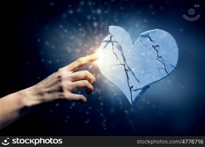 Broken stone heart. Close up of human hand breaking stone heart