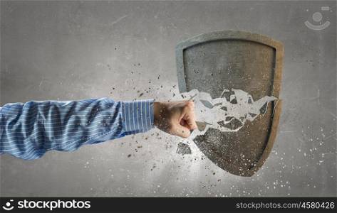 Broken stone shield . Conceptual image with hand breaking old stone shield