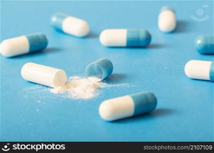 broken white antibiotic capsule blue background
