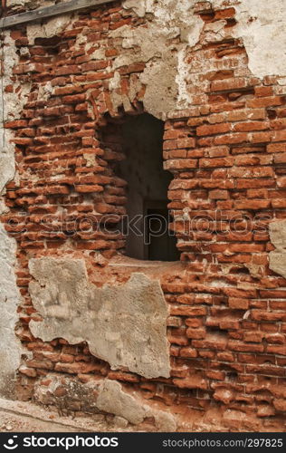 Broken window frame of ruined damaged abandon neglected country house brick wall with ruined stucco masonry closeup