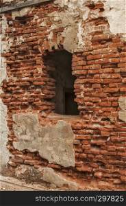 Broken window frame of ruined damaged abandon neglected country house brick wall with ruined stucco masonry closeup