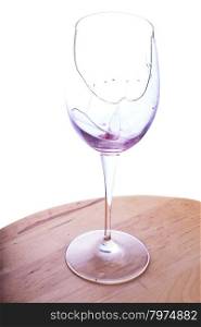 Broken wine glass over table, white background, vertical image