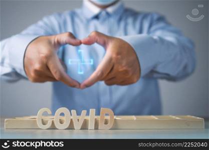 Broker presents about Covid insurance. Heart shape with hands. Wood texts are on the table. Medium close up shot.