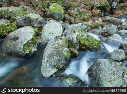 Brook and big rocks with moss in autumn