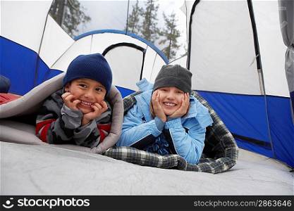 Brother and sister (7-12) in tent (portrait)
