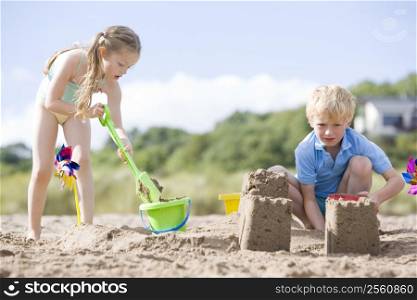 Brother and sister at beach making sand castles