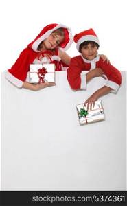 Brother and sister dressed in Santa Claus outfits