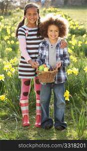 Brother And Sister Having Easter Egg Hunt In Daffodil Field