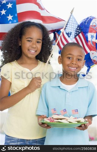 Brother and sister on fourth of July with flag and cookies smiling