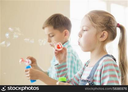 Brother and sister playing with bubble wands at home