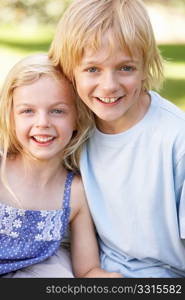 Brother and sister pose in a park