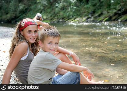 Brother and sister resting on a riverside
