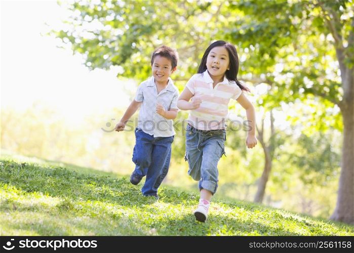 Brother and sister running outdoors smiling