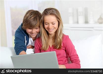 Brother and sister using laptop computer at home