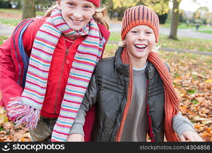 Brother and sister walking through park together, smiling