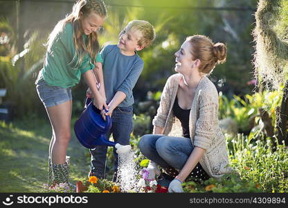 Brother and sisters watering plants on allotment