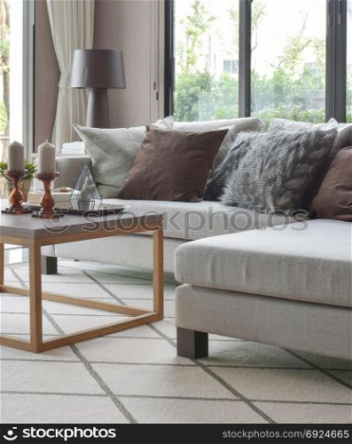 Brown and gray pillows on beige sofa and wooden frame table in modern living room