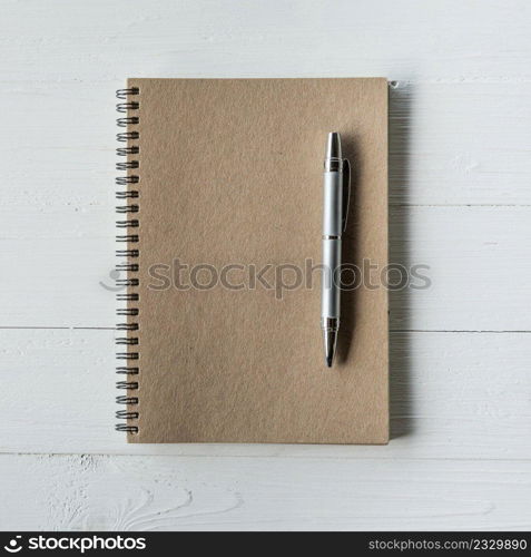 brown book and pen on white wood table