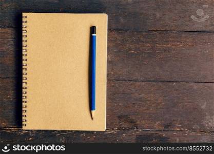 brown book and pencil on wood table background with space