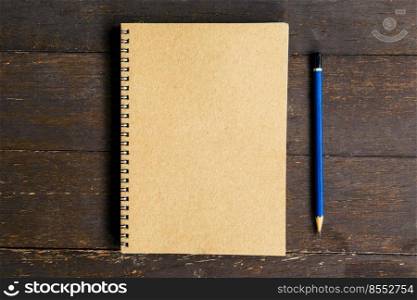 brown book and pencil on wood table background with space