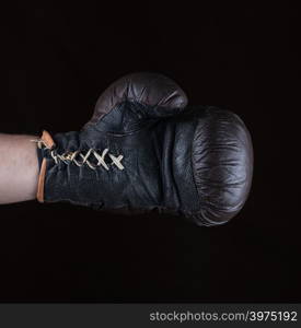 brown boxing glove dressed on man&rsquo;s hand, black background