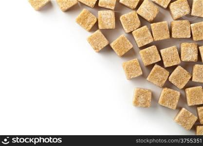 Brown cane sugar cubes on white background with copy space. Top view
