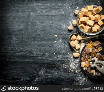 Brown cane sugar. On a black rustic background.. Brown cane sugar. On black rustic background.
