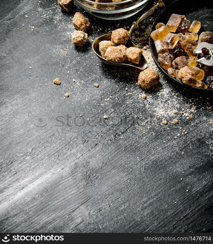 Brown cane sugar. On a black rustic background.. Brown cane sugar. On black rustic background.