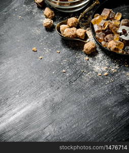 Brown cane sugar. On a black rustic background.. Brown cane sugar. On black rustic background.