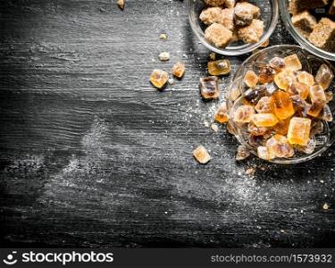 Brown cane sugar. On a black rustic background.. Brown cane sugar. On black rustic background.