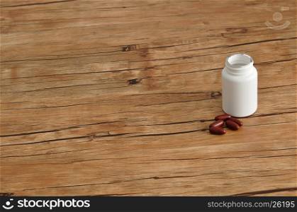 Brown capsules with a white plastic bottle isolated on a wooden background