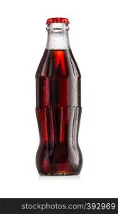 Brown carbonated drink in a wet bottle with a red cap isolated on white background. Brown carbonated drink in wet bottle with red cap