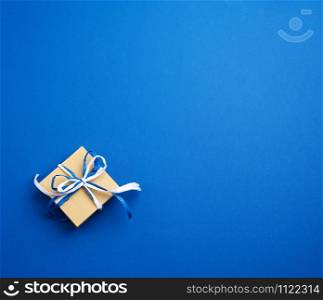 brown cardboard gift square box, bows on a blue background, top view. Festive concept, copy space