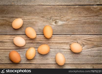 brown chicken eggs on a rustic weathered wooden table, top view with a copy space