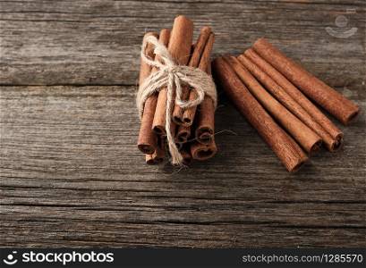 brown cinnamon sticks tied in a bun on a gray wooden background, tasty and fragrant spice, close up